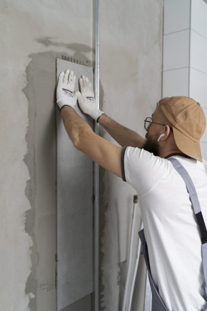 Des artisans qui rénovent un mur en placo