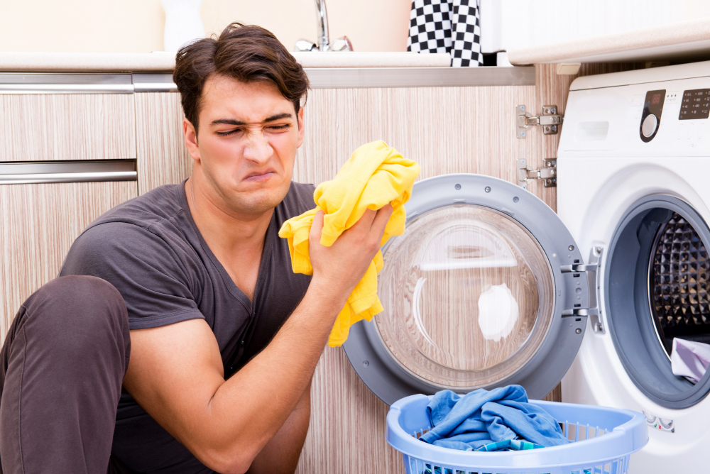 Une homme assis devant une machine à laver